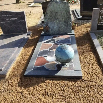Grafmonument met ruwe steen en een bal