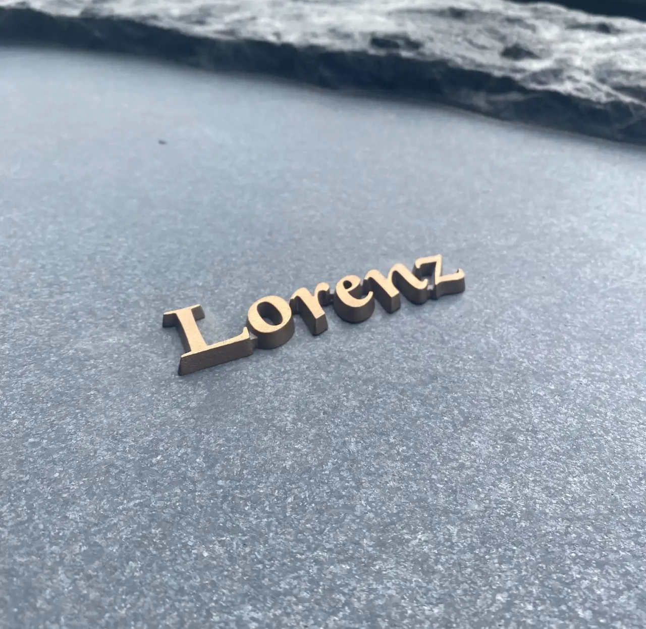 Bronzen letters op een grafsteen van ruw graniet