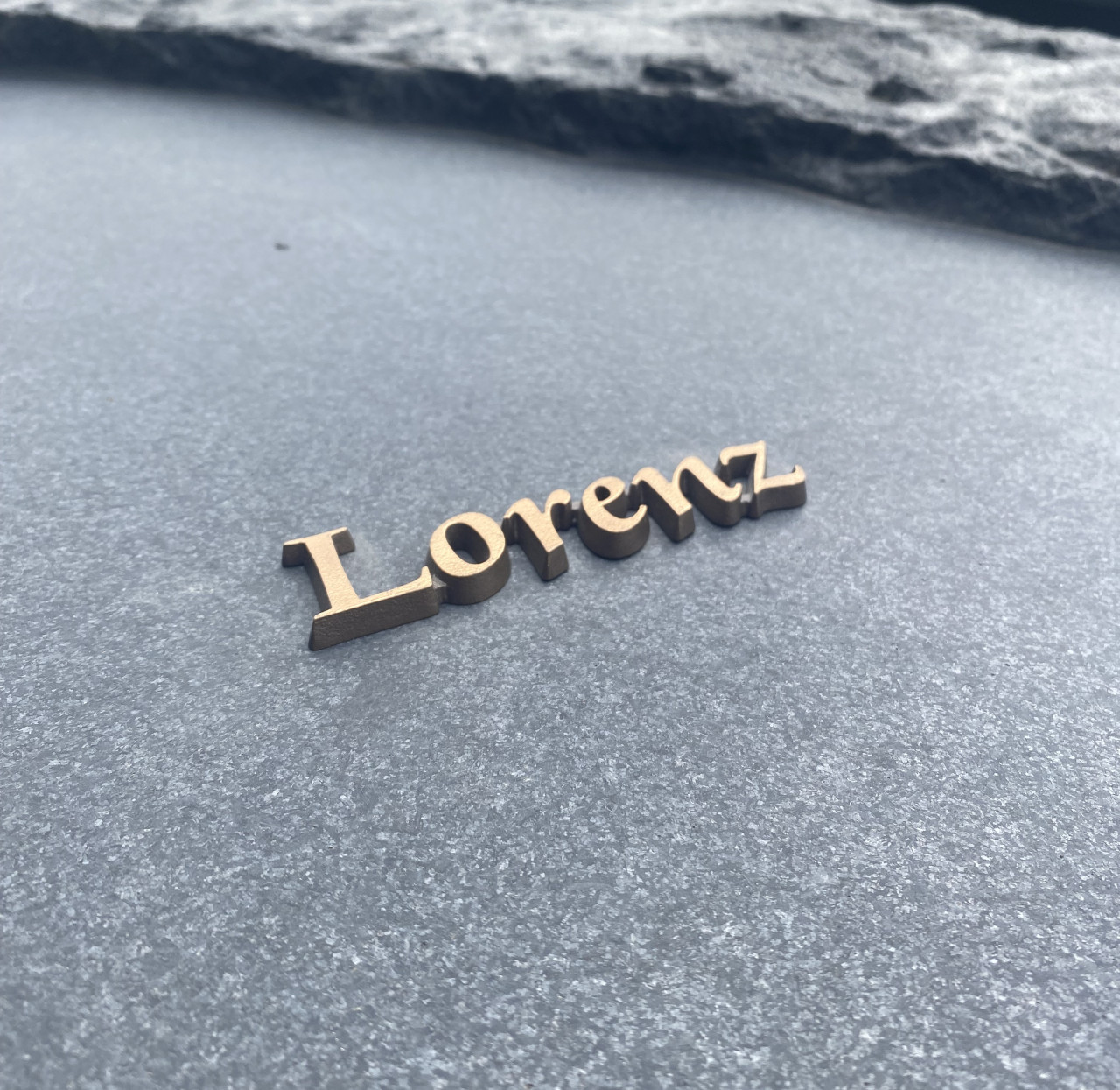 Bronzen letters op een grafsteen van ruw graniet